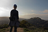Rückansicht eines Wanderers mit Blick auf das Hollywood-Schild und die Santa Monica Mountains in der Ferne, Los Angeles, Kalifornien, USA