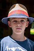 Head and shoulders portrait of young boy wearing straw hat