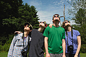 Kleine Gruppe von Menschen, die eine Sonnenfinsternisbrille tragen, während sie eine partielle Sonnenfinsternis betrachten
