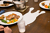 Cup of Spilled Milk on Dinner Table
