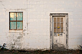 Verfallenes Schlackenblockgebäude mit verwitterten Türen und Fenstern
