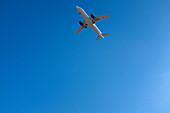 Tiefblick auf ein Verkehrsflugzeug vor blauem Himmel