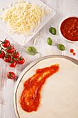 Ingredients for pizza: dough, tomato sauce, tomatoes, cheese and basil