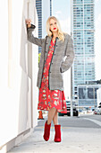 Young blond woman in red floral dress and checked coat