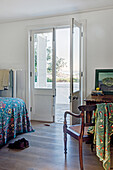 Colorful bedspread on bed in bedroom with balcony