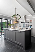 Kitchen island with grey cabinets and hanging glass dome light