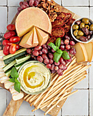 Cheese platter with olives, dip, tomatoes, cucumber, grapes and walnuts