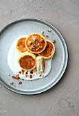 Syrniki (Russian cream cheese pancakes) with sour cream and caramelized nuts