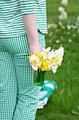 Person carrying glass with daffodils