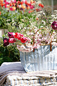 Blumenarrangement im Korb auf Decke und Kissen