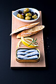 Oil sardines, lemons, toasted bread and pickled olives