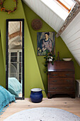 Dachzimmer mit grünen Wänden, Holzsekretär und Spiegel