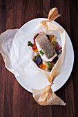 Sea bass with vegetables baked in parchment paper