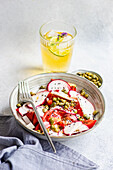 Vegetable salad with organic tomatoes, radishes, and capers, served with lemonade