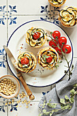 Puff pastry tartlets with zucchini, cherry tomatoes, cream cheese and pine nuts