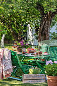 Gedeckter Gartentisch mit Kuchen und Blumen unter einem Baum