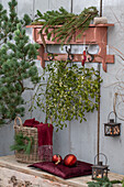 Weihnachtsdeko auf der Terrasse mit Tannenzweigen,  Mistelzweige, Kerzen und Christbaumkugeln an rustikaler Garderobe hängend