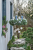 Adventskranz geschmückt mit Federn und Federkugeln auf der Terrasse aufgehängt