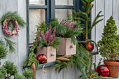 Weihnachtsdeko auf der Terrasse mit Tannenzweigen, Erika, Fichtenbäumchen, Kiefernzweigen, Christbaumkugeln, Herbstkranz, Zapfen