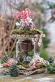 Weihnachtsetagere aus Baumscheiben mit Moos, Weihnachtskugeln im Glas, Zuckerstangen und Schleifen