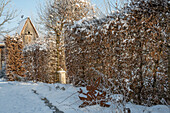 Verschneiter winterlicher Garten mit Rankbogen und Vogelhaus