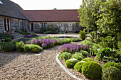 Yard with wood sided buildings, gravel path and gardens