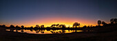 Farbenfroher Sonnenuntergang am Wasserloch. Camelthorn Lodge. Hwange-Nationalpark. Simbabwe.