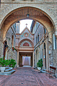Italien, Umbrien, Assisi. Bogengang und Weg zur katholischen Kirche Monastero della Santa Croce.