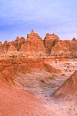 The sunset colors reflect off the cliffs and peaks of the hoodoos in Badlands National Park.