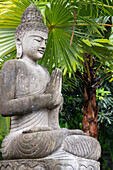 Indonesien, Bali. Buddha-Statue mit grünen Palmen.