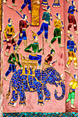Laos, Luang Prabang. Mosaikwandbild, das einen auf einem Elefanten reitenden Mann darstellt, der sich auf die Jagd oder den Kampf vorbereitet.