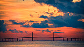 The Skyway Bridge over the Gulf of Mexico with the reds and oranges of the sunrise in the sky.