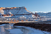 USA, Utah. Fisher Towers, La Sal Mountains, and canyon walls reflected in the icy Colorado River.