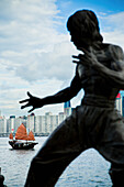 Traditional Chinese Junk Boat In Background. Bruce Lee Memorial Statue, View Of Victoria Harbour, Hong Kong Island Skyline, From Tsim Sha Tsui, Kowloon; Tsim Sha Tsui, Kowloon, Hong Kong, China