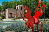 Außenansicht einer Baptistenkirche und Skulptur eines roten Pferdes in Taos, New Mexico, USA