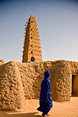 Niger, Sahara-Wüste, Region Agadez, erbaut 1515, restauriert 1844. Sie beherbergt das renommierte Zentrum für Islamische Studien und ihr 30 Meter hohes Minarett ist das höchste aus Lehm gemauerte Minarett in Afrika; Agadez, aus Lehm, verschleierter Tuareg-Mann geht an der Großen Moschee vorbei