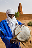 Niger, Sahara Desert, Agadez Region, Tuareg drummer standing next to Agadez Grand Mosque; Agadez
