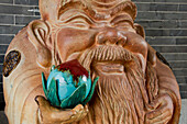 China, Guangdong, Dragon Kiln Nanfeng pottery; Foshan, Statue of smiling man holding nut