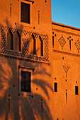 Marokko, Dattelpalmenschatten an der Wand der Hauptkasbah des Dar Ahlam Hotels in der Abenddämmerung; Skoura