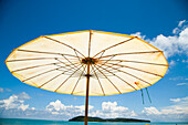 Malaysia, Pantai Cenang (Cenang Strand); Pulau Langkawi, Sonnenschirm am Strand mit Blick aufs Meer und kleiner Insel im Hintergrund