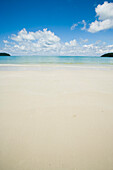 Malaysia, Pantai Cenang (Cenang Strand); Pulau Langkawi, Inseln im Hintergrund, weite Aussicht auf weißen Sandstrand und blauen Himmel