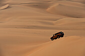 VAE, Abu Dhabi, Geländewagen fährt über Sanddünen; Liwa