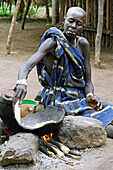 Eine Mursi-Stammesfrau kocht 'tila' (ein traditionelles Gericht aus Mais oder Sorghum). Makki /Süd-Omo / Region der südlichen Nationen, Nationalitäten und Völker (Äthiopien).