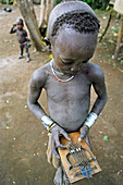 Mursi tribal boy playing a 'chongku'. Makki / South Omo / Southern Nations, Nationalities & People's Region (Ethiopia).