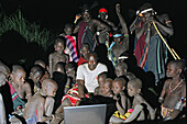 Gruppe von Mursi Stammesangehörigen, die den ersten Mursi-eigenen Laptop-Computer, der in der Nacht in Betrieb genommen wird, in Ehrfurcht betrachten. Makki / Süd-Omo / Region der südlichen Nationen, Nationalitäten und Völker (Äthiopien).