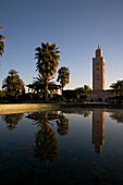 Minarett der Koutoubia-Moschee spiegelt sich in einem Springbrunnen in der Morgendämmerung; Marrakesch, Marokko