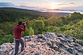 A man takes a photograph of sunrise along Skyline Drive, Shenandoah National Park, Virginia.