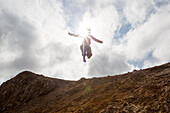 A woman jumps from a hill at the mud pots geothermal area of Lake Myvatn.; Iceland