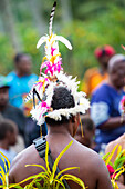 Blick von hinten auf eine traditionelle Tänzerin mit einem Kopfschmuck aus tropischen Vogelfedern bei einer Aufführung auf der Insel Karkar in der Bismarcksee vor der Nordküste Papua-Neuguineas; Karkar Island, Provinz Madang, Papua-Neuguinea