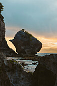 Silhouette einer großen Felsformation und Küstenlinie des Diamond Beach in der Dämmerung, Nusa Penida, Bali, Indonesien; Nusa Penida, Bali, Indonesien